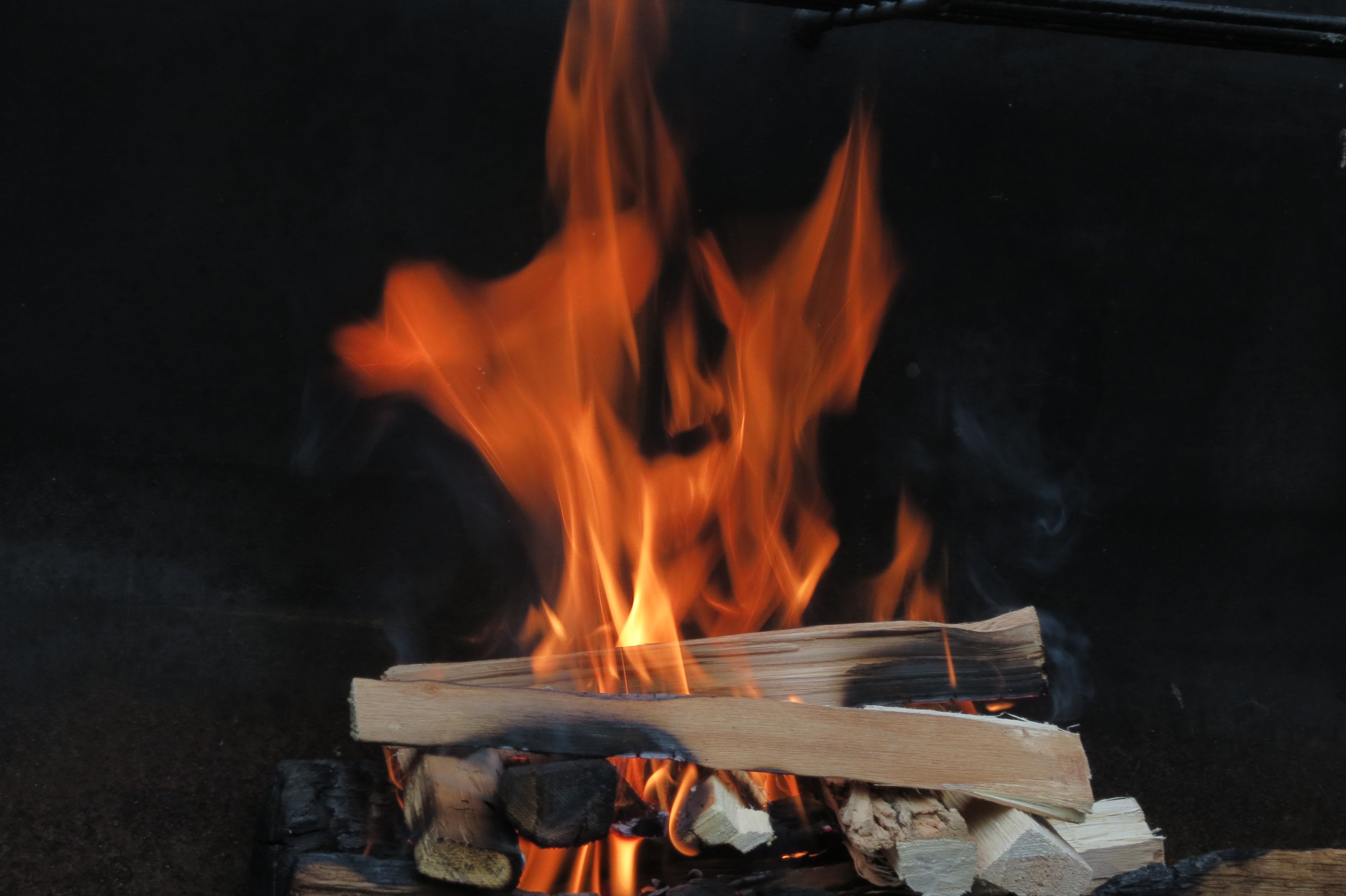 Captivating image of a campfire with vibrant orange flames and wooden logs.