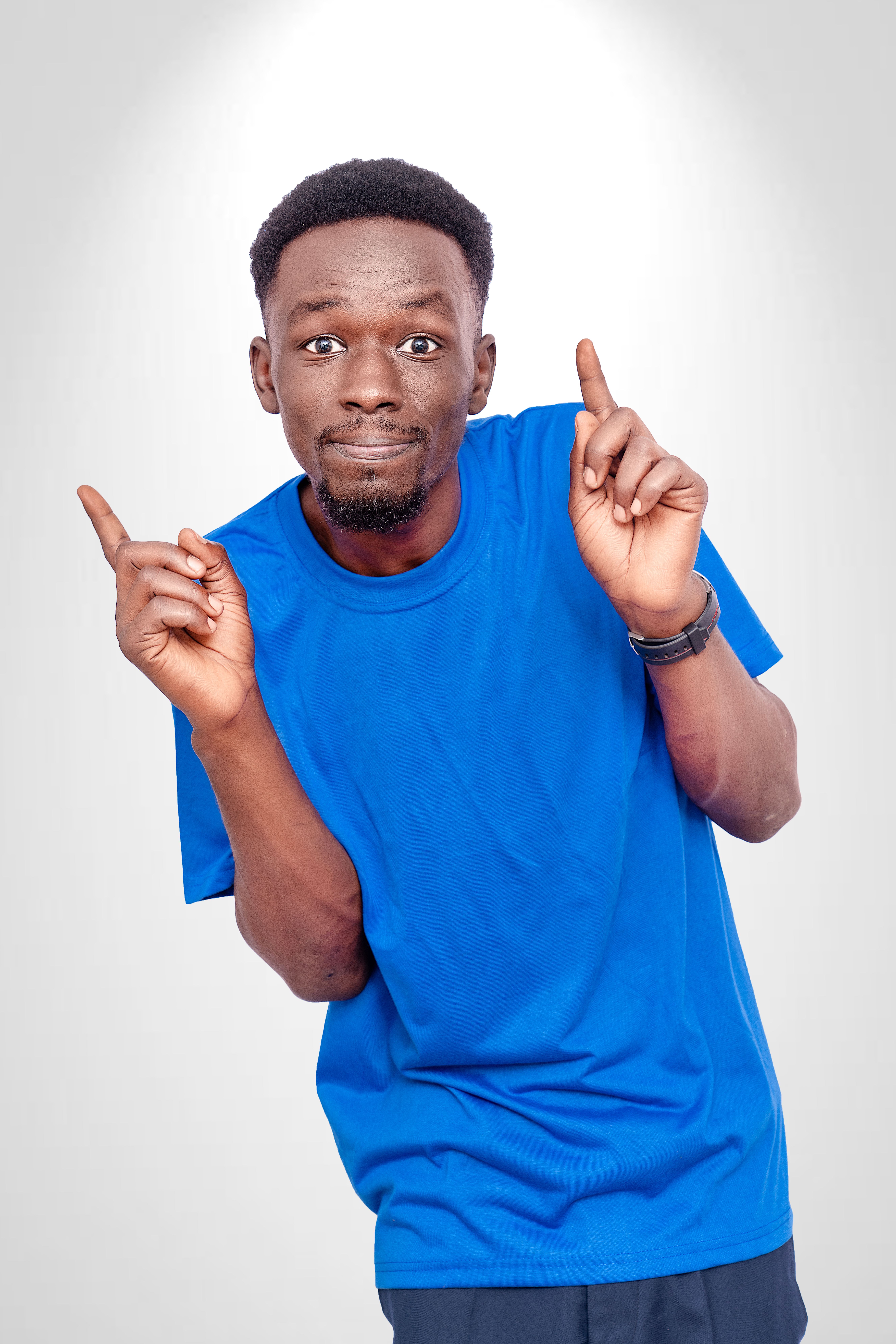 Smiling man in a blue shirt pointing upwards against a white background.