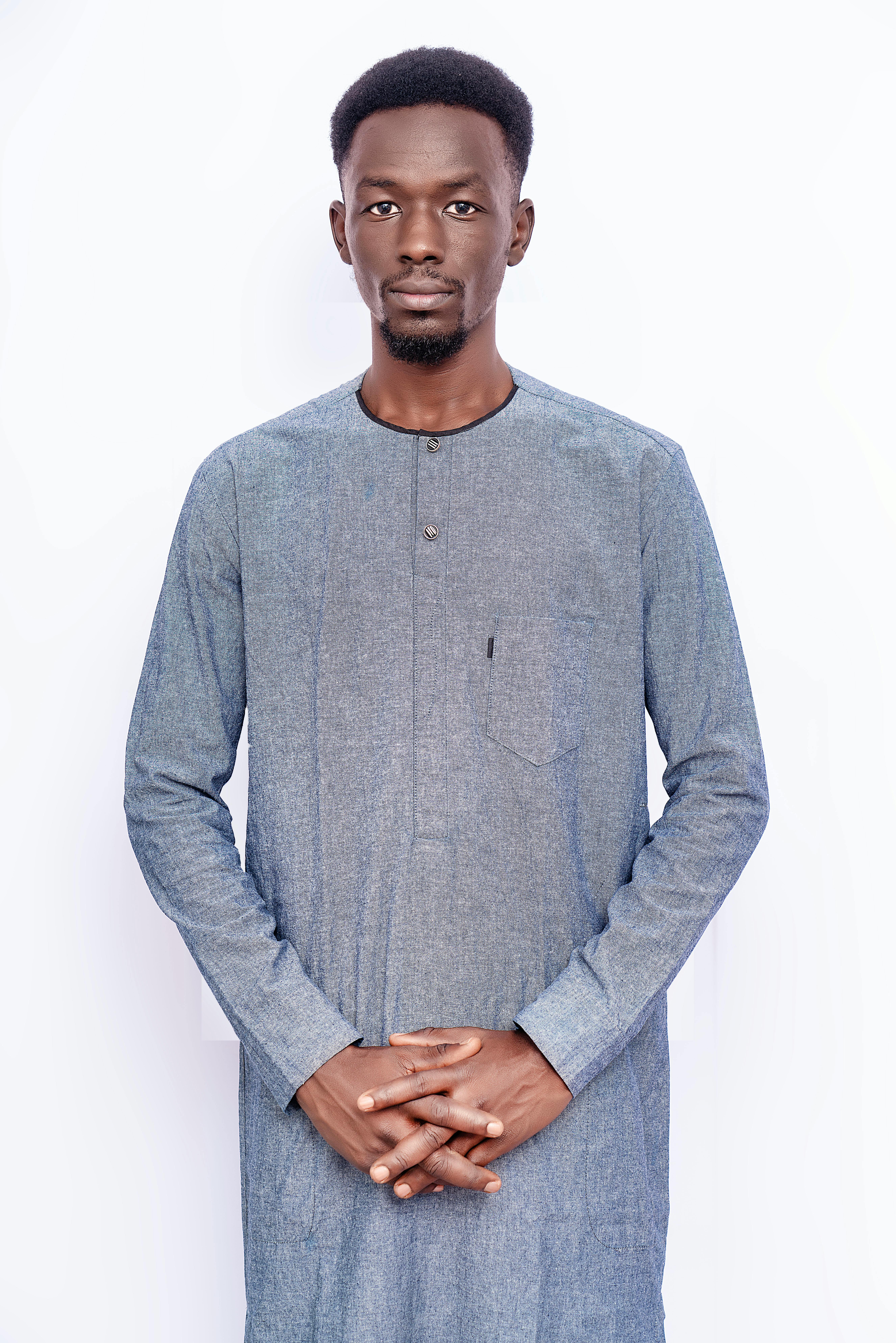 Studio portrait of a man in traditional blue attire against a white background.