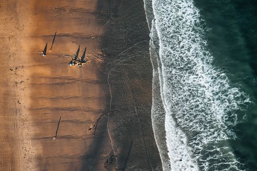 Stunning aerial shot of a sandy beach with waves and distant people.