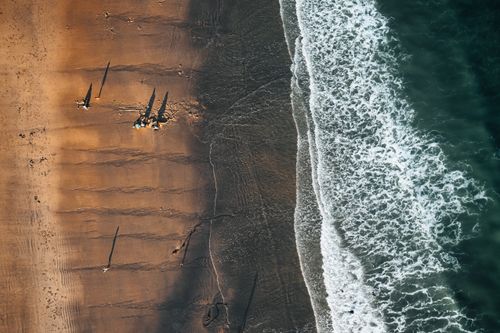 Free Stunning aerial shot of a sandy beach with waves and distant people. Stock Photo