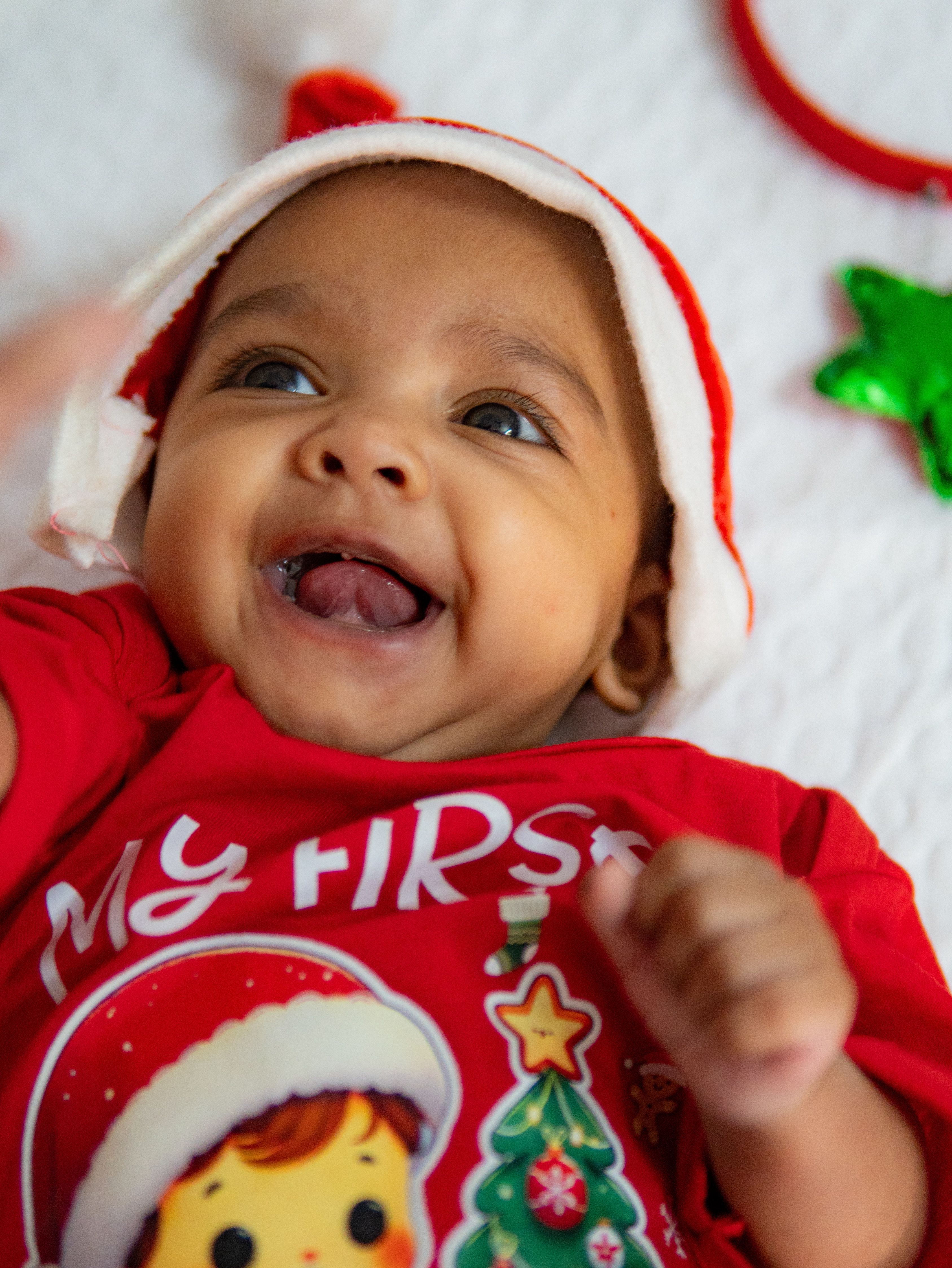 happy baby wearing a santa hat celebrating first christmas