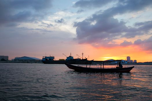 Tranquil boat silhouette against a vibrant coastal sunset, creating a serene seascape scene.