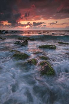 Stunning sunset with waves crashing over mossy rocks on the shore of Rize, Türkiye.