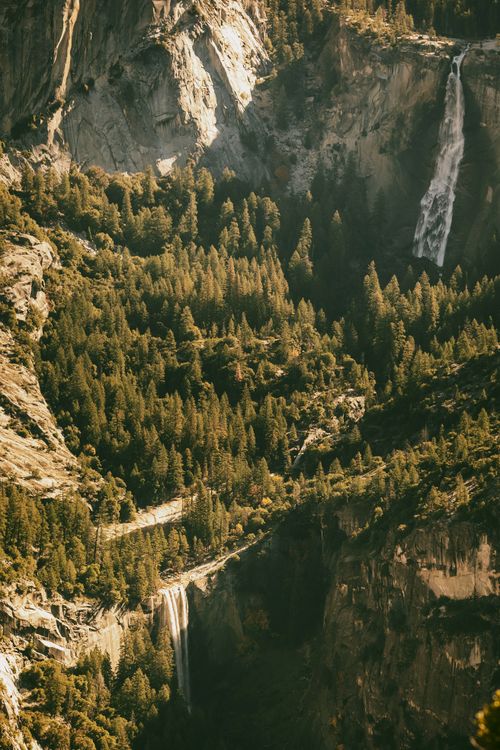 Free A breathtaking view of Yosemite Valley showcasing waterfalls and lush forest scenery under fall lighting. Stock Photo