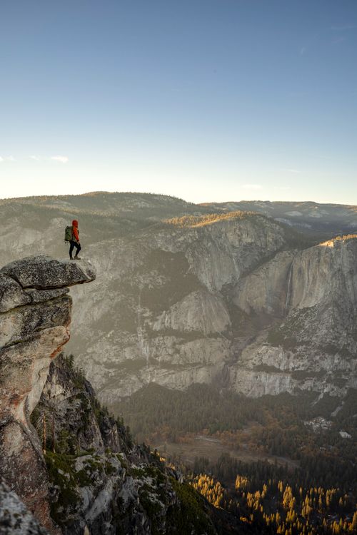 Free A lone hiker stands on a cliff edge, overlooking the vast Yosemite Valley during fall. Stock Photo
