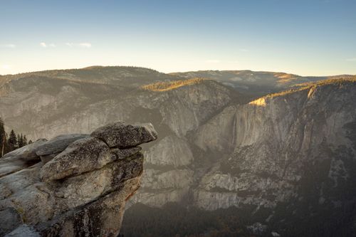 Free Breathtaking view of Yosemite's rocky cliffside and distant mountains at sunset. Stock Photo