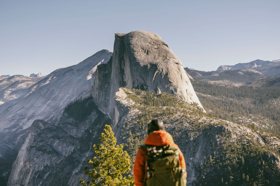 Hiker admires the majestic view of Half Dome in Yosemite National Park during fall.