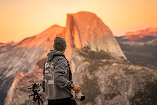 A photographer captures the stunning beauty of Half Dome in Yosemite during a serene fall sunset.