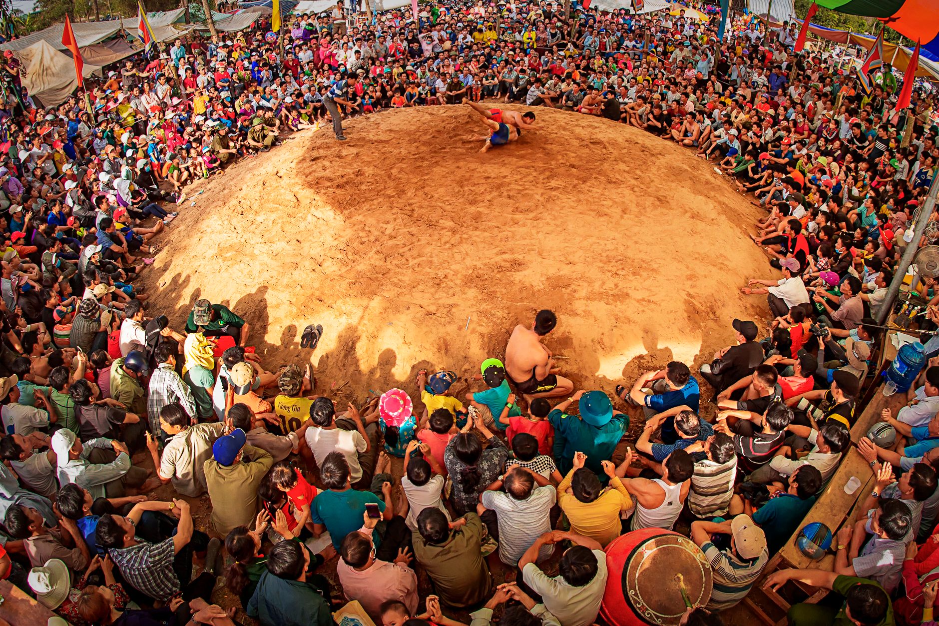 A vibrant scene of a traditional wrestling festival in Đắk Lắk, Vietnam, capturing dynamic cultural interactions.