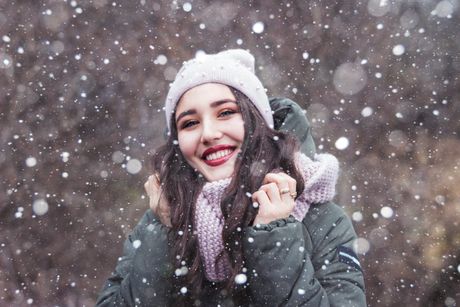 Smiling woman outdoors in falling snow &mdash; photo by Наталия Котович on Pexels