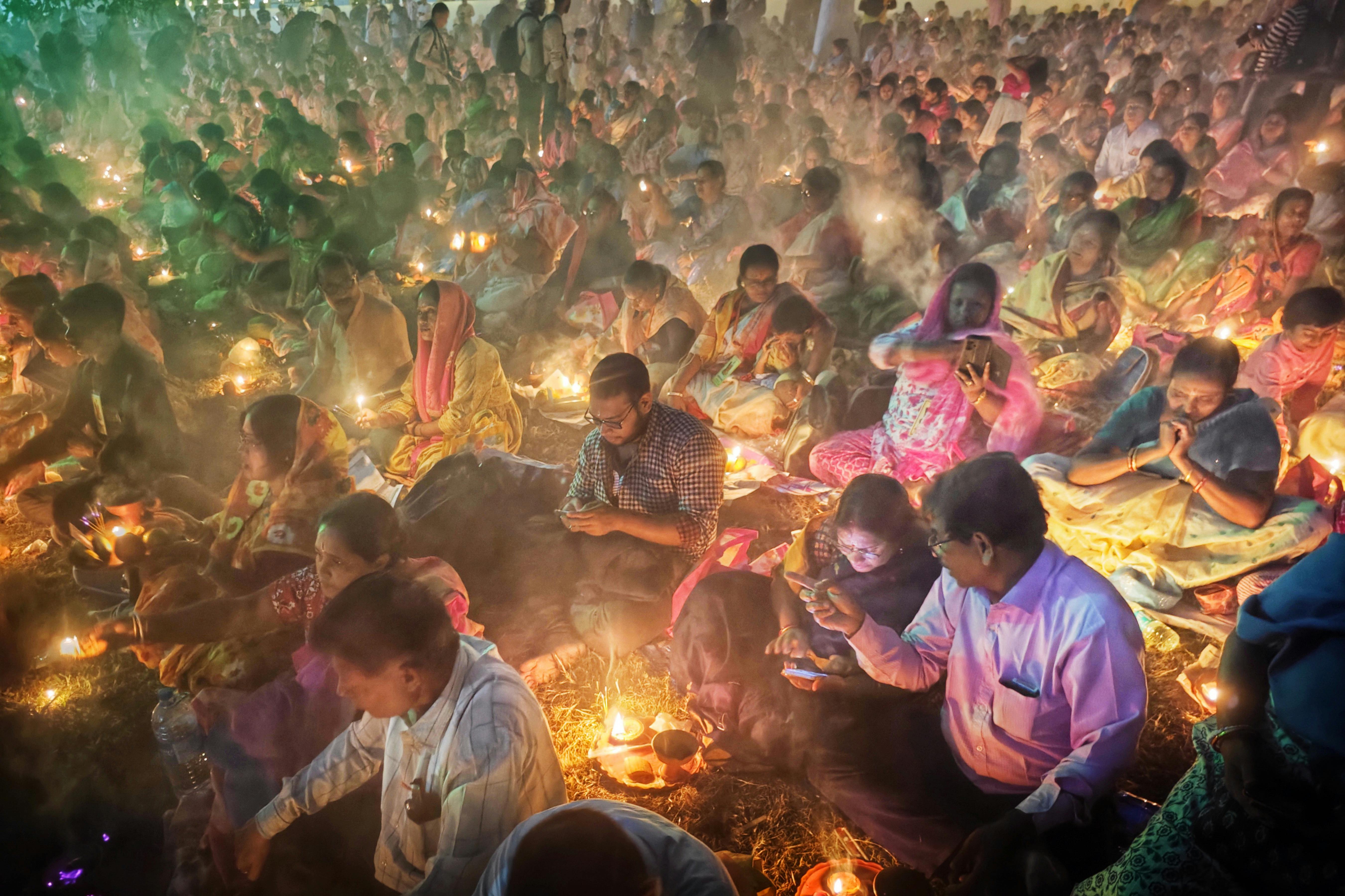 Captivating scene of a traditional festival in Kolkata, India with people gathered and lighting lamps.