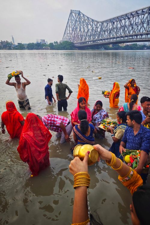 Free People engaging in traditional rituals at the Hooghly River, with Howrah Bridge in the background, Kolkata, India. Stock Photo