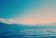 宁静的海景中，远处皮划艇运动员的轮廓映衬着柔和的天空，周围环绕着温柔的海浪