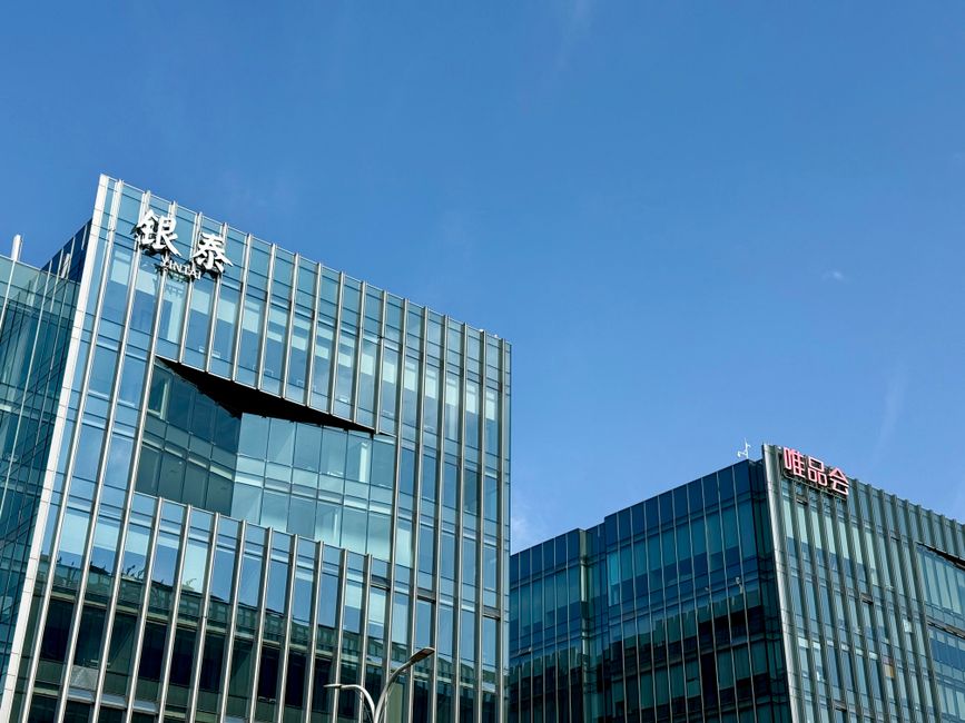 中国上海の澄んだ青空の下にあるモダンなガラス張りのファサードの建物のクローズアップ。
