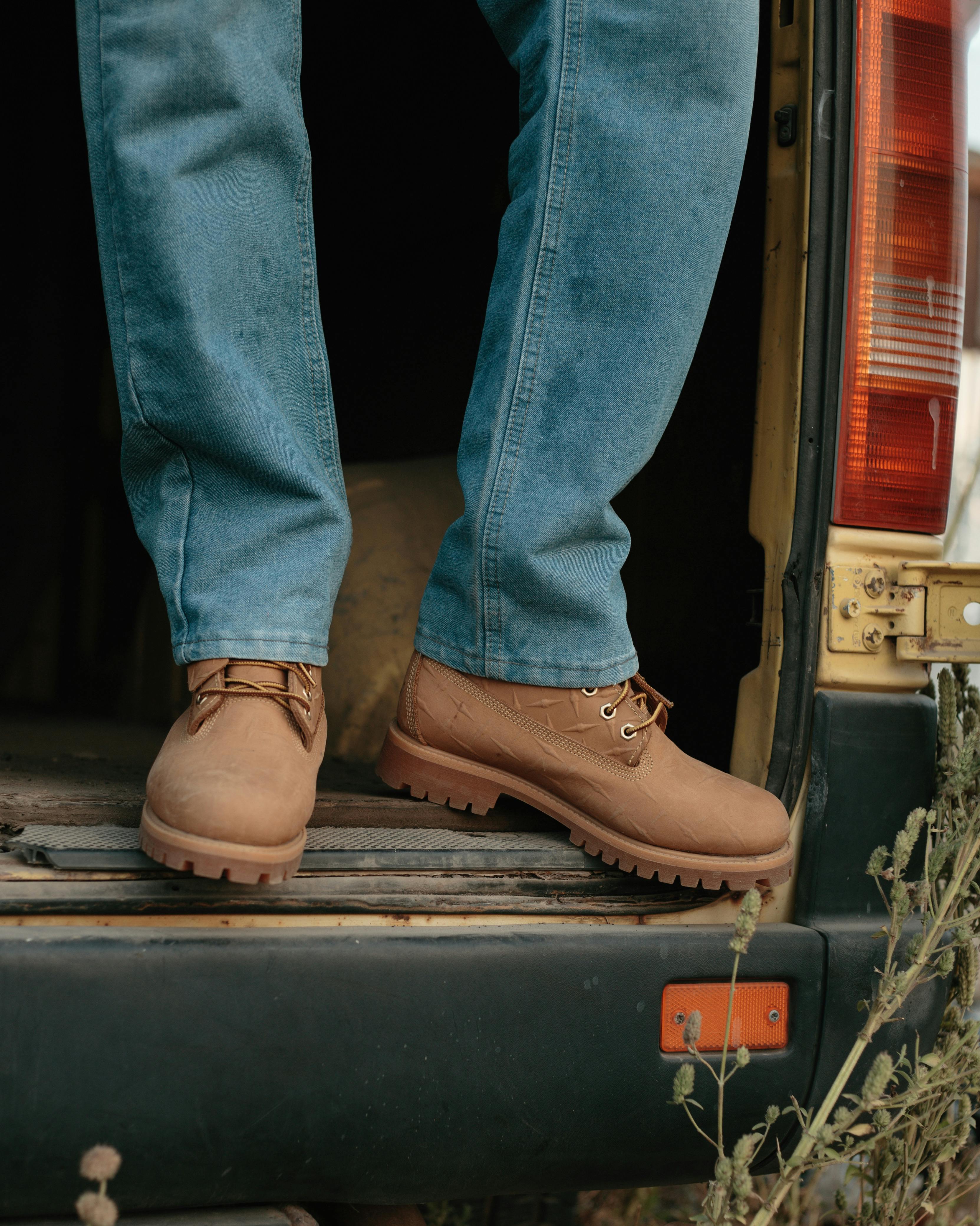Gratis Hombre con jeans y botas de pie en la puerta de una camioneta, al aire libre. Foto de stock