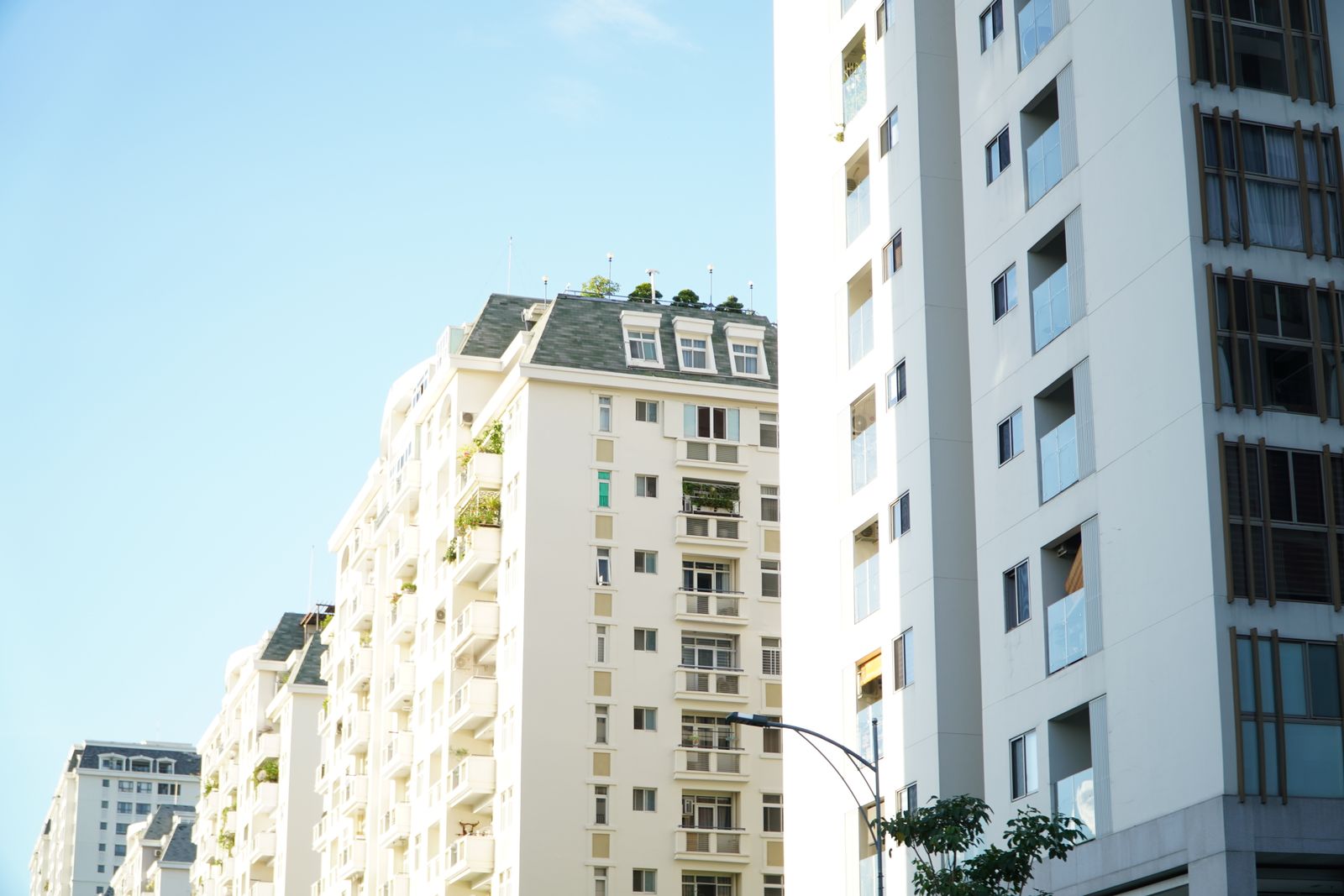 Façades d'immeubles résidentiels blancs avec balcons, vus depuis la rue par temps clair