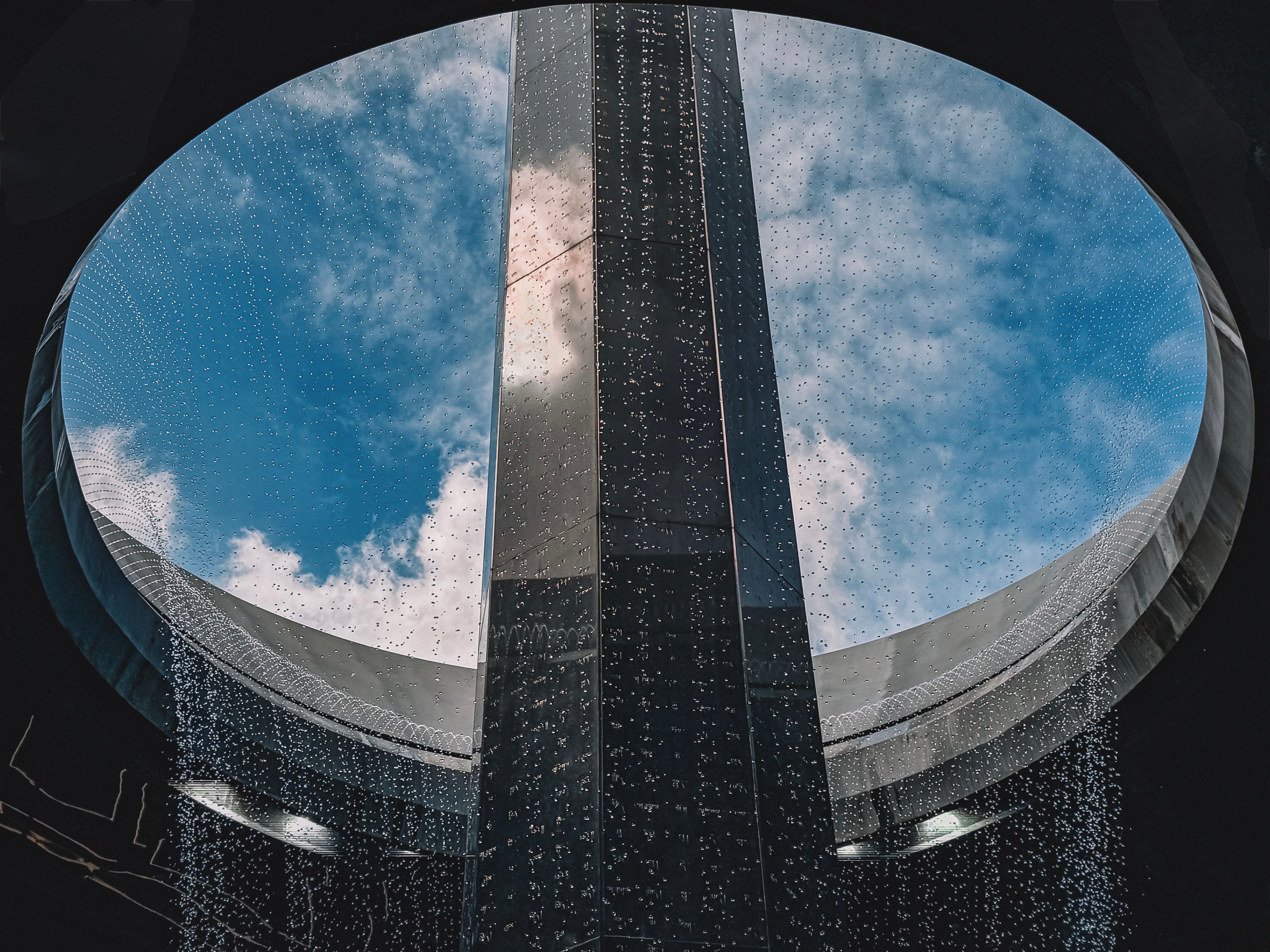 Captivating sky view through a circular architectural structure with cascading water design.