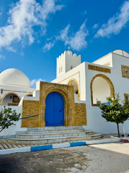 Free Captivating view of a Tunisian building with iconic blue door under a clear sky. Stock Photo