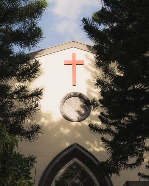 Free Sunlit view of an ancient church facade framed by trees in Bengaluru, India. Stock Photo