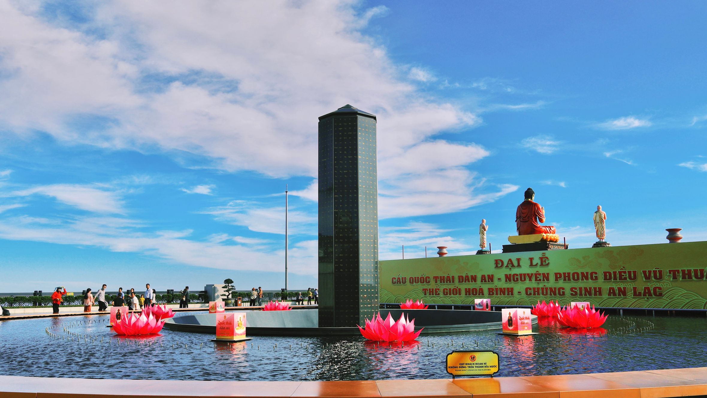 Colorful outdoor view of Ba Den Mountain with lotus pond and statues under a bright sky.