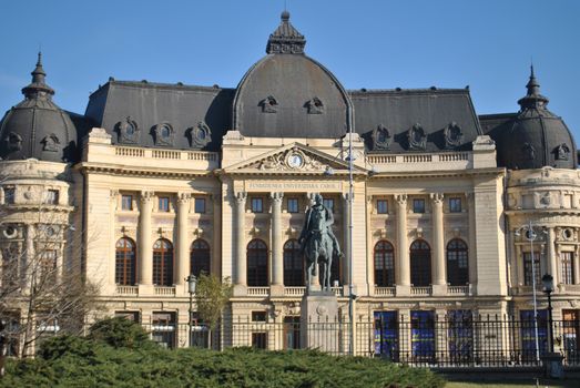 Elegant historic university building featuring an equestrian statue in a sunny outdoor setting.