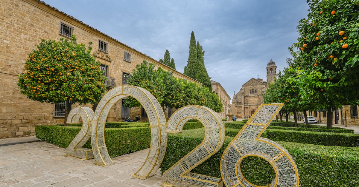 Scenic view of Úbeda, Spain featuring historic architecture and a large 2026 installation amidst orange trees and manicured hedges.