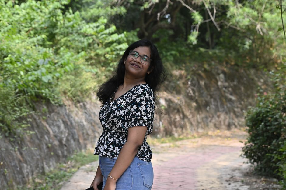 A woman enjoying a sunny day outdoors, surrounded by greenery.
