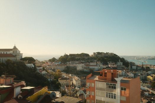 A scenic view of Lisbon with São Jorge Castle and rooftops under a soft sunrise light.