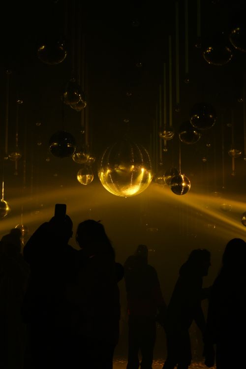 Free Silhouettes at a festive Berlin light installation with glowing orbs and golden ambiance. Stock Photo