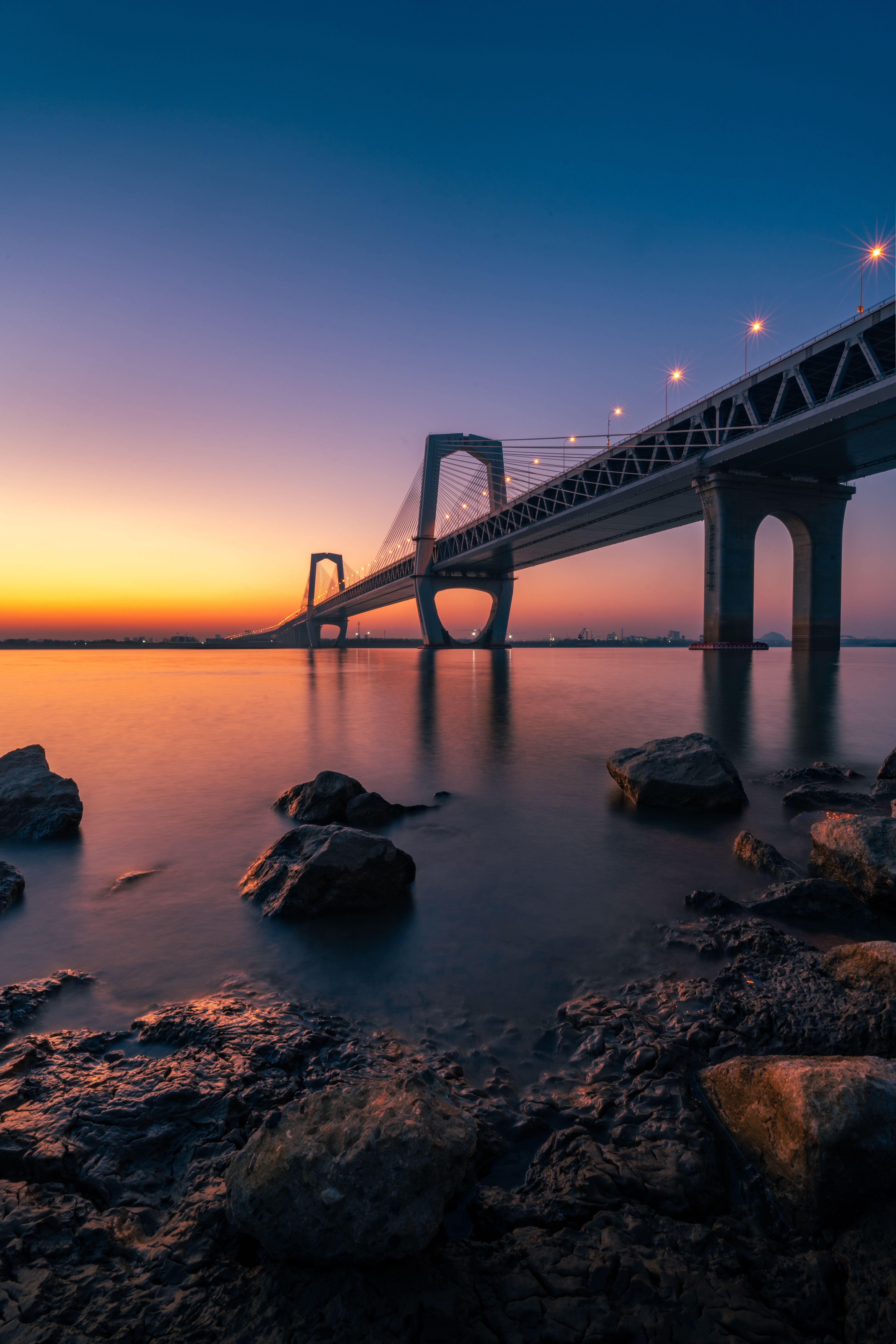 A stunning view of a bridge over tranquil waters with a vibrant sunset sky.