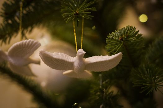 White dove ornament on Christmas tree branch, symbolizing peace and holiday spirit.
