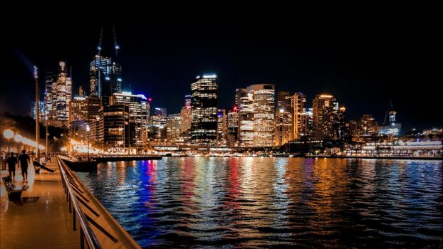 Explore the breathtaking Sydney skyline at night with vibrant reflections and city lights illuminating the harbor.
