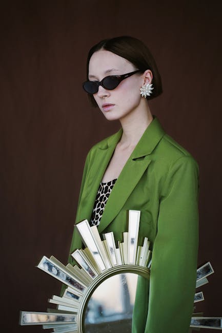 Woman Wearing Sunglasses and Green Blazer While Holding Sunburst Wall Mirror