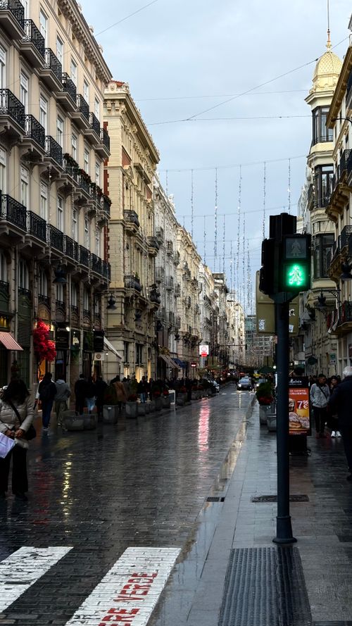 Free People walking down a wet street in Valencia's historic district at dusk. Stock Photo