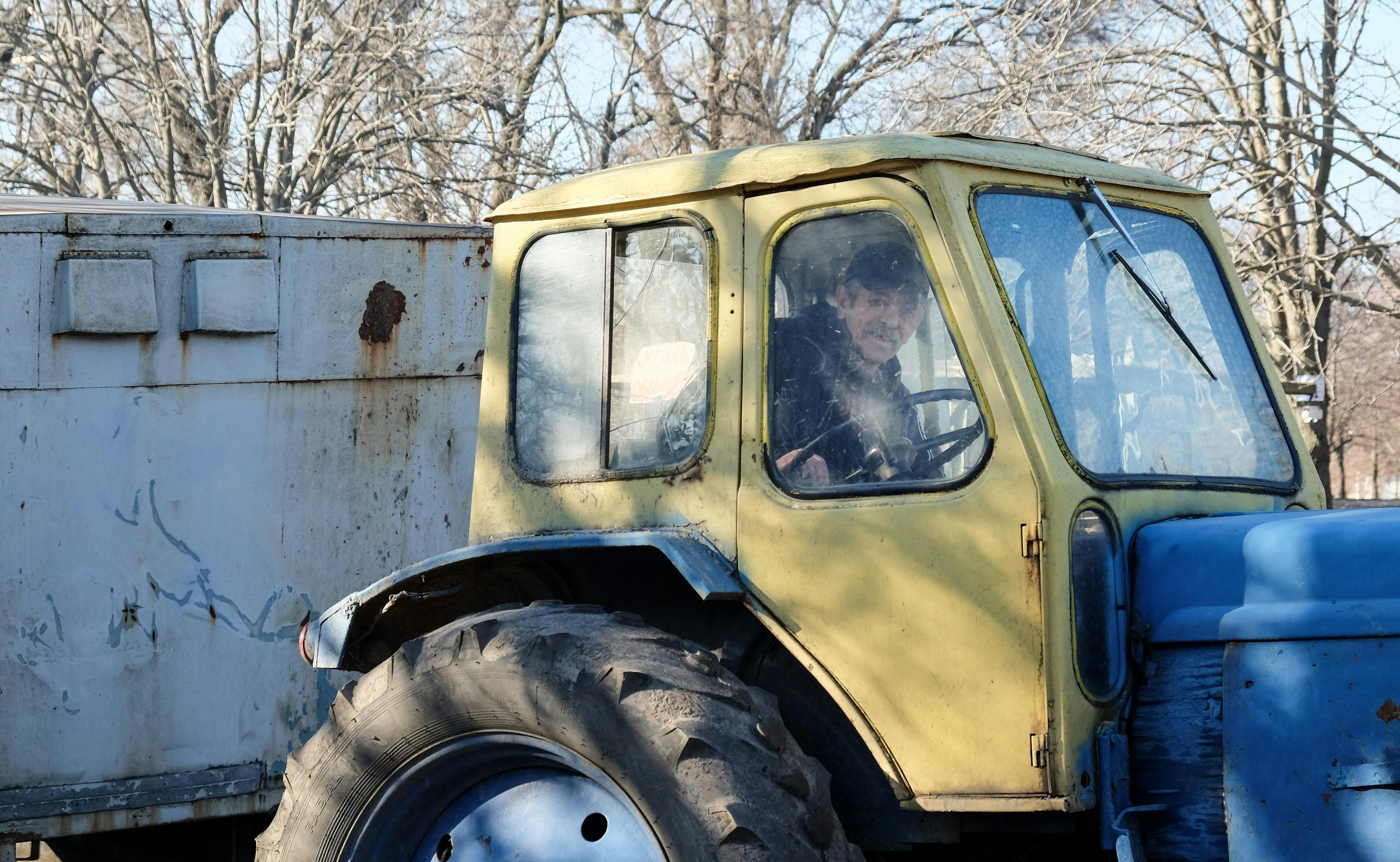 A farmer operating a vintage tractor in rural Ukraine during winter.