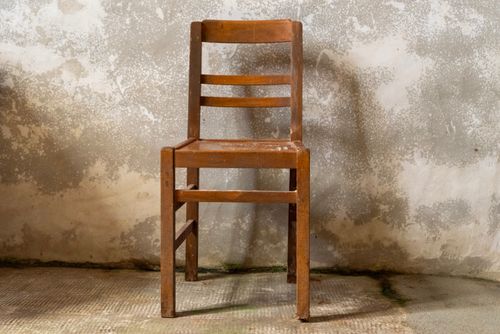Free A single wooden chair placed against a rustic, textured wall in an indoor setting. Stock Photo