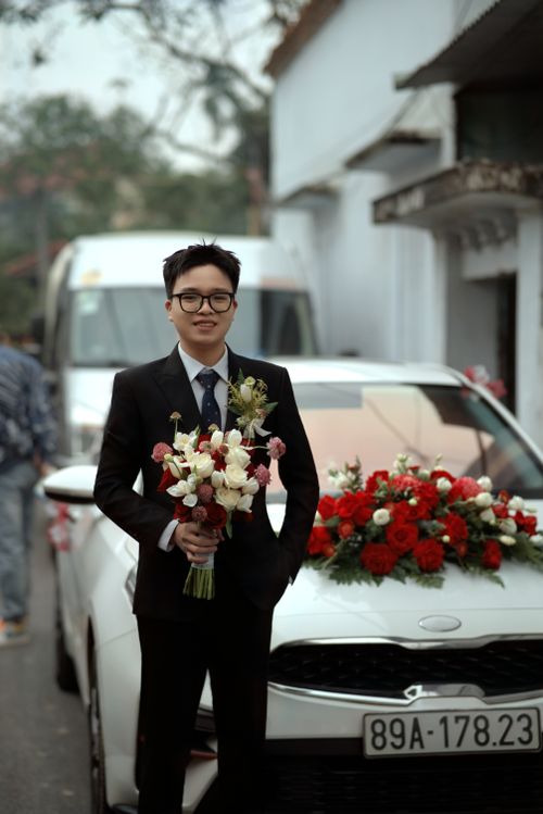 Free A man in formal attire holds a bouquet by a flower-decorated car. Stock Photo
