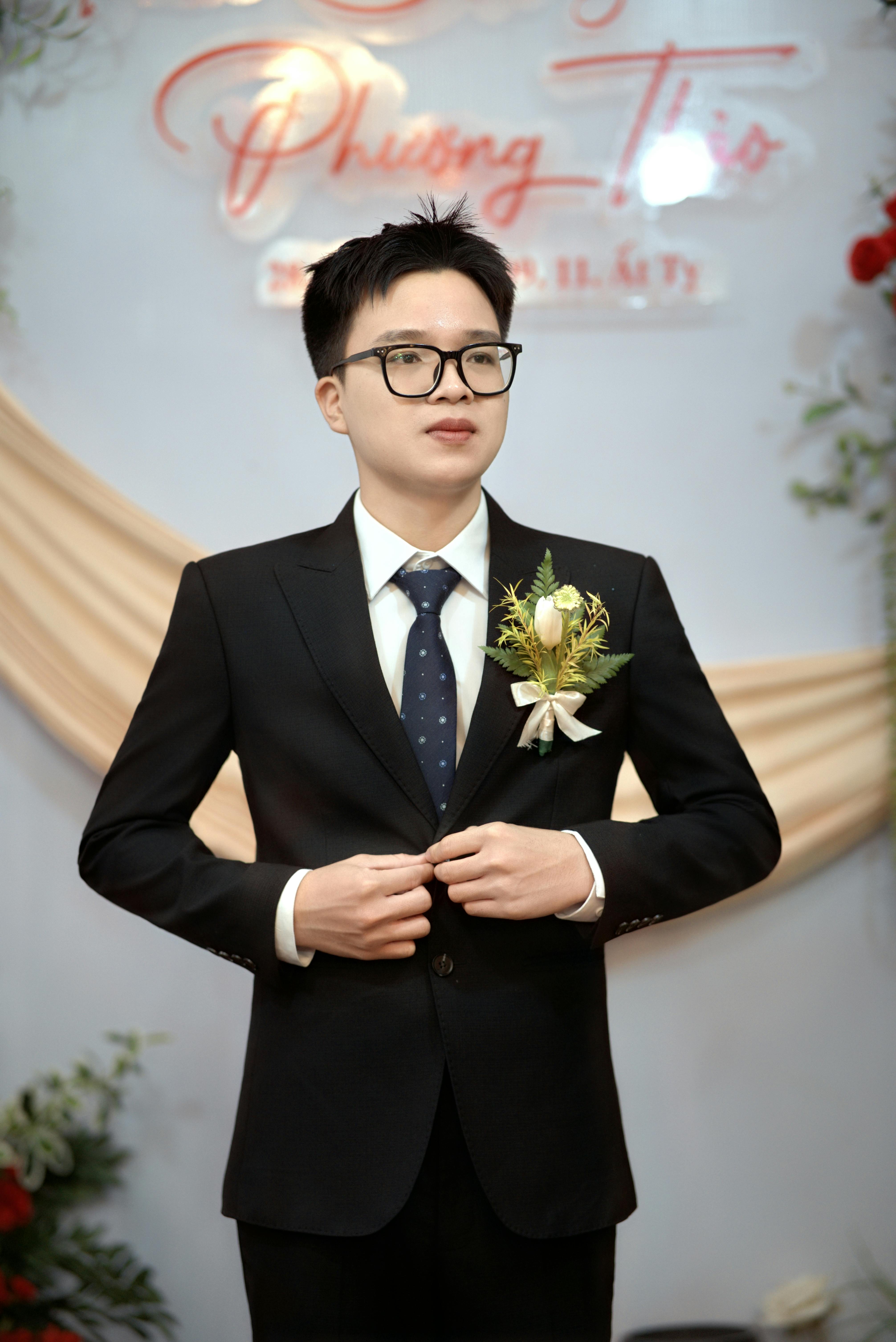 Young man in a suit adjusting jacket, ready for a formal event indoors.