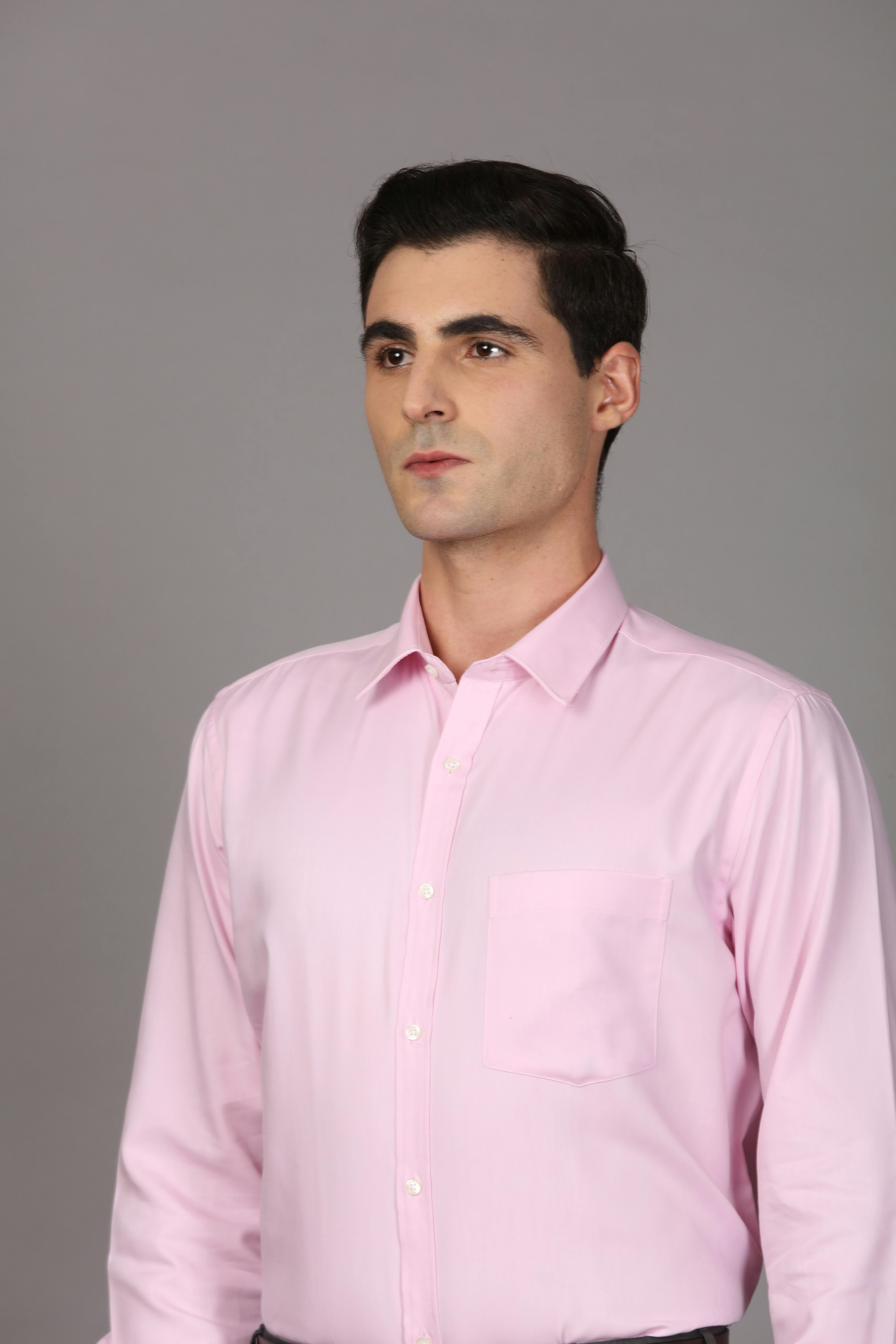 ingyenes Portré egy fiatal felnőtt férfiról, aki rózsaszín inget visel semleges háttér előtt. Stockfotó