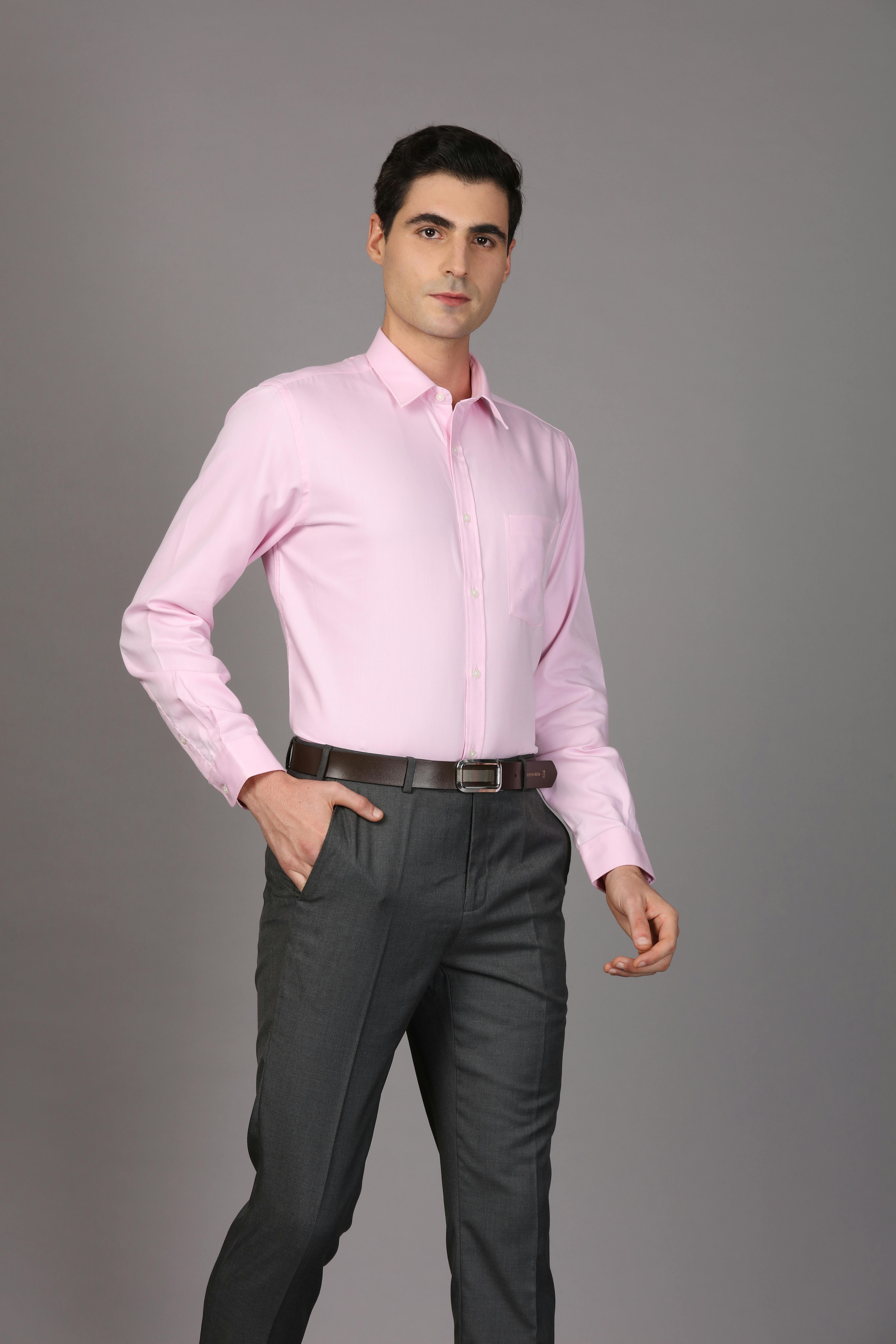 Kostenlos Selbstbewusster Mann in hellrosa Hemd und grauer Hose, der einen stilvollen, professionellen Look präsentiert. Stock-Foto