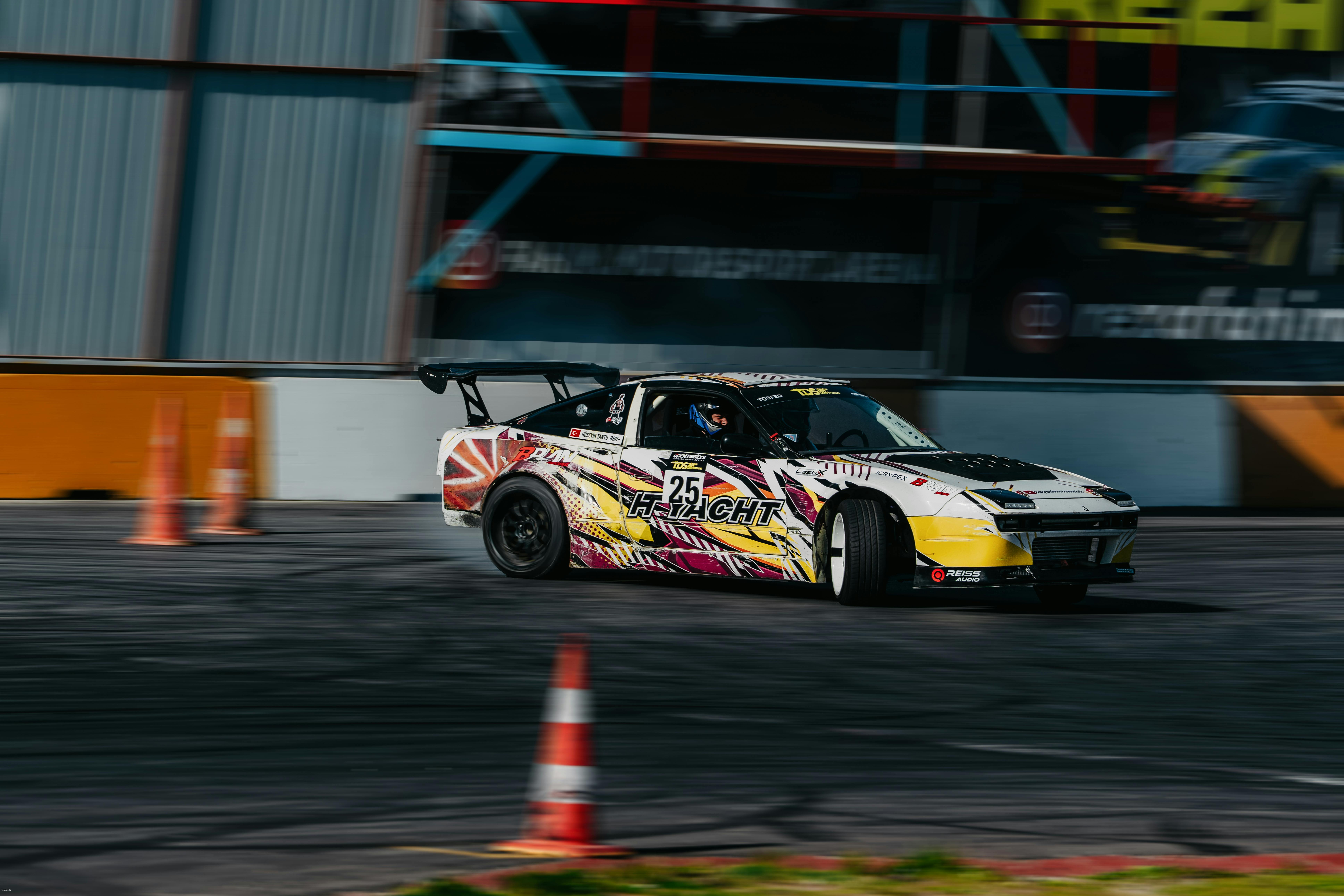 Race car expertly drifting around cones on a track during a race event. Vibrant colors and motion blur enhance action.