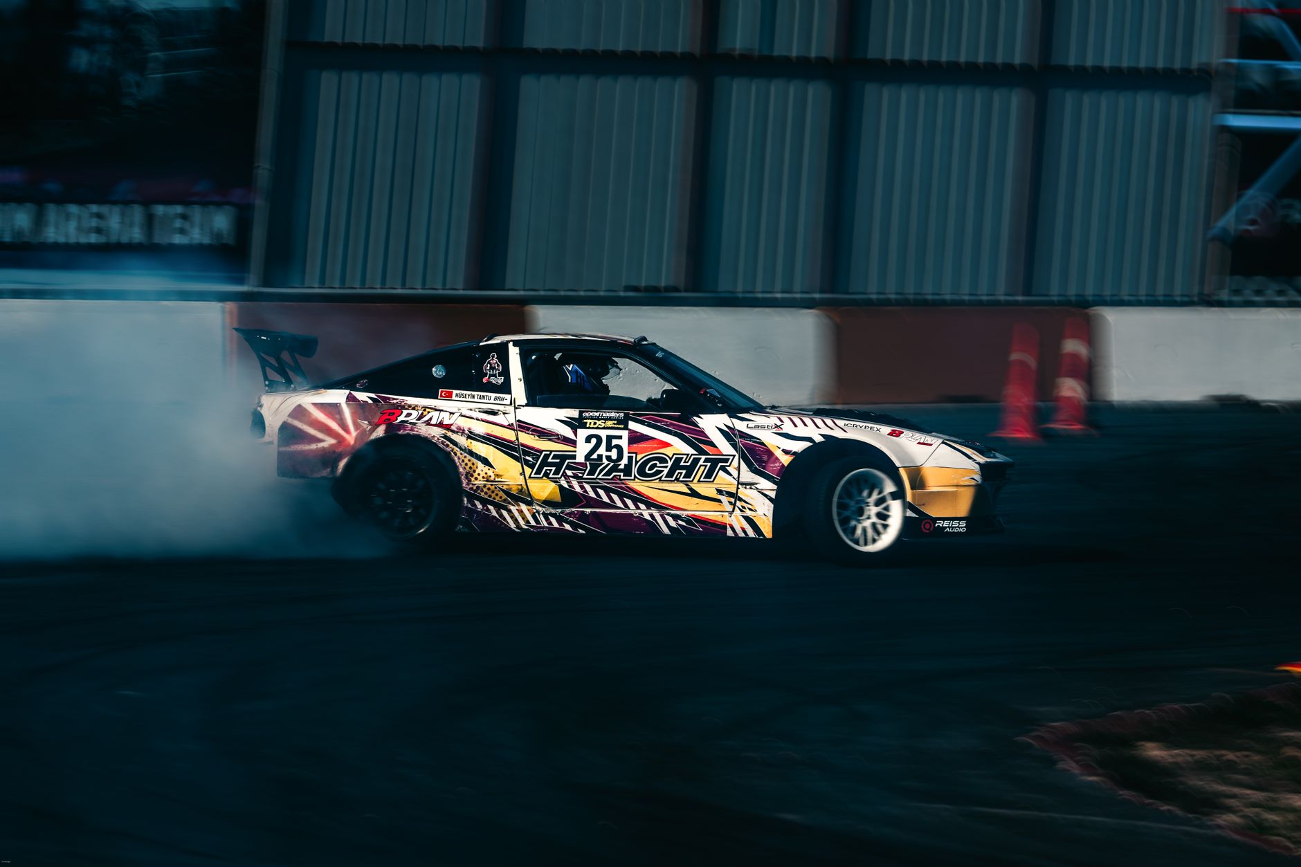 Dynamic shot of a car drifting on a racing track, leaving a trail of smoke.