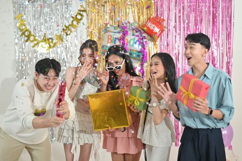 Free Group of friends celebrating a birthday indoors with gifts and decorations. Stock Photo