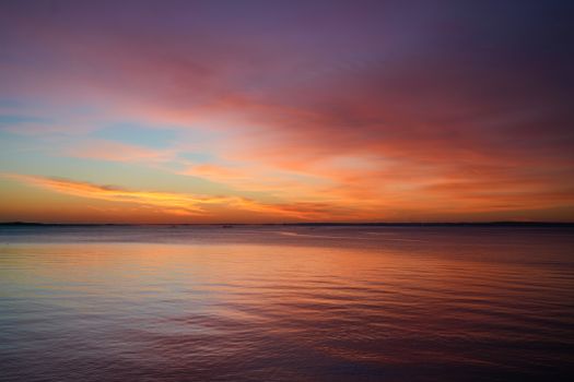 Vibrant sunset reflecting over calm ocean waters, creating a warm and serene atmosphere.