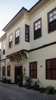 Beautiful two-story house with classic architecture and potted plants on a sunny day.
