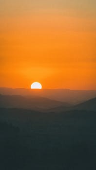 A beautiful sunset casting warm hues over a mountainous landscape.
