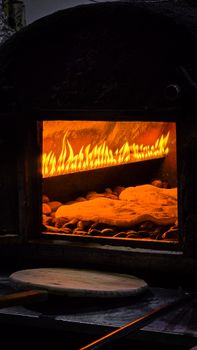 A traditional stone oven with a vivid glowing fire baking bread, showcasing rustic culinary craftsmanship.