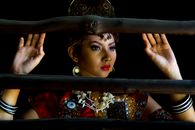 Elegant portrait of a woman in traditional Indonesian attire framed by wooden bars.