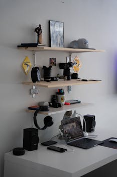 A sleek, modern home office setup featuring shelves with tech gadgets and a laptop on a desk.